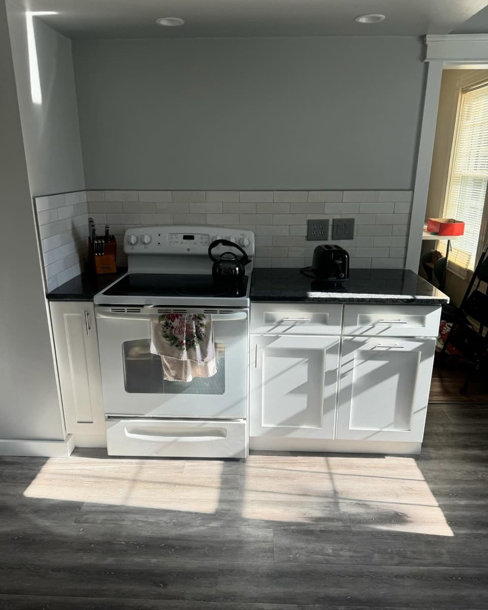 Finished kitchen by Farley Construction — white shaker cabinets, granite counters and a subway tile backsplash