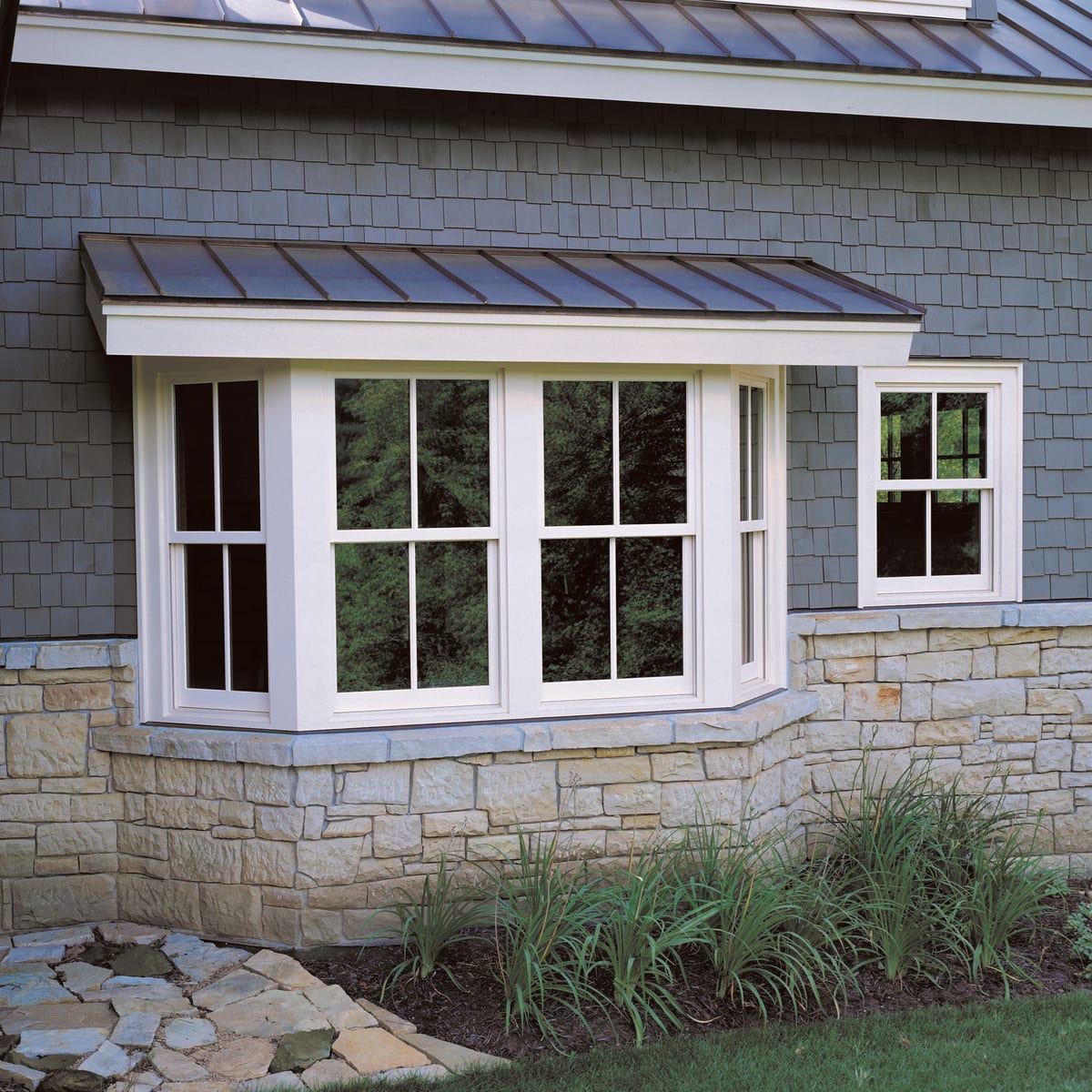 Window installation by Farley Construction — a bay window with a standing-seam copper roof, beside a matching double-hung window